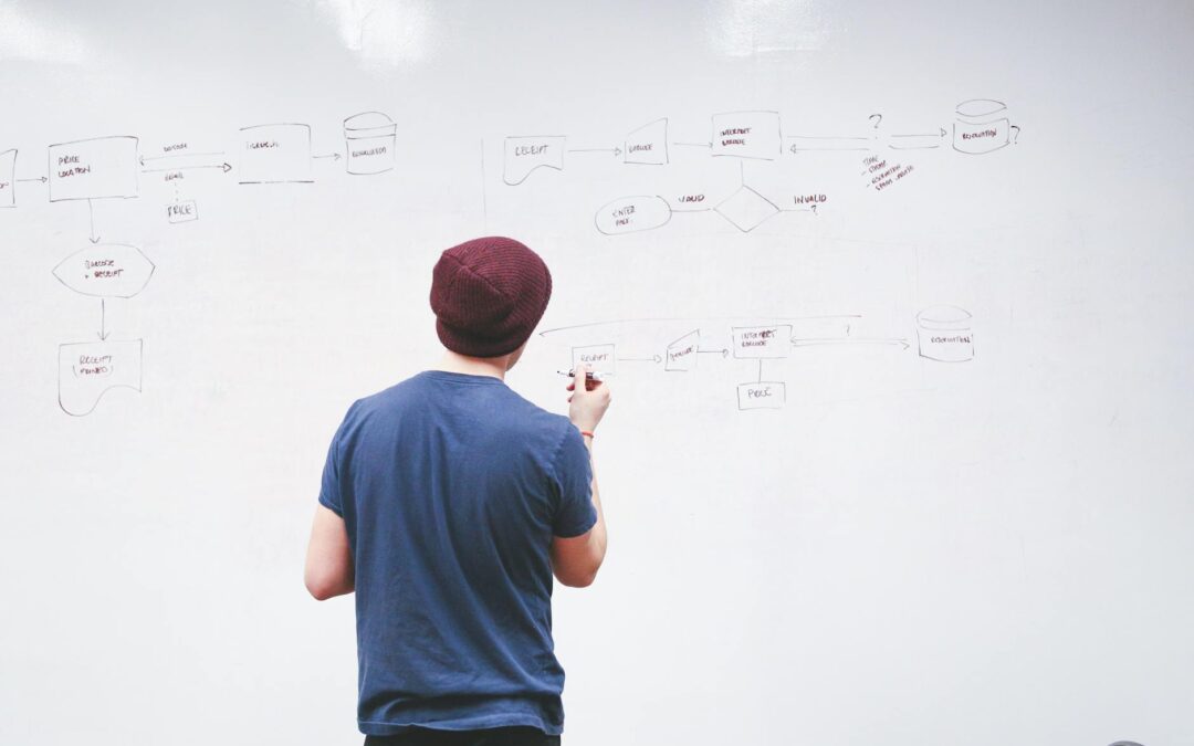 man standing while holding red marker pen facing marker board